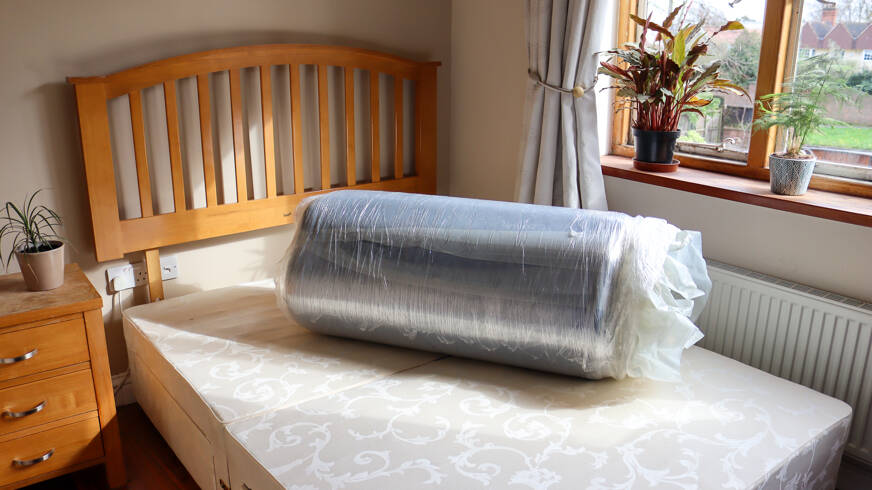 zoma mattress rolled up on bed